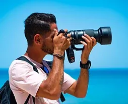 Professional photographer framing a shot against a bright sky in Makkah