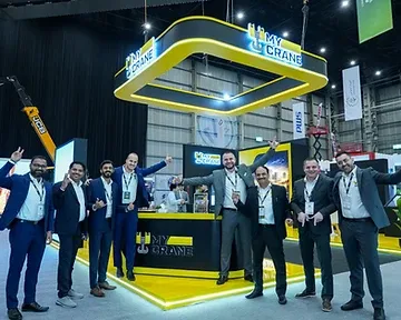 Group of delegates gathered in front of a branded exhibition stand in an industrial hall in Riyadh